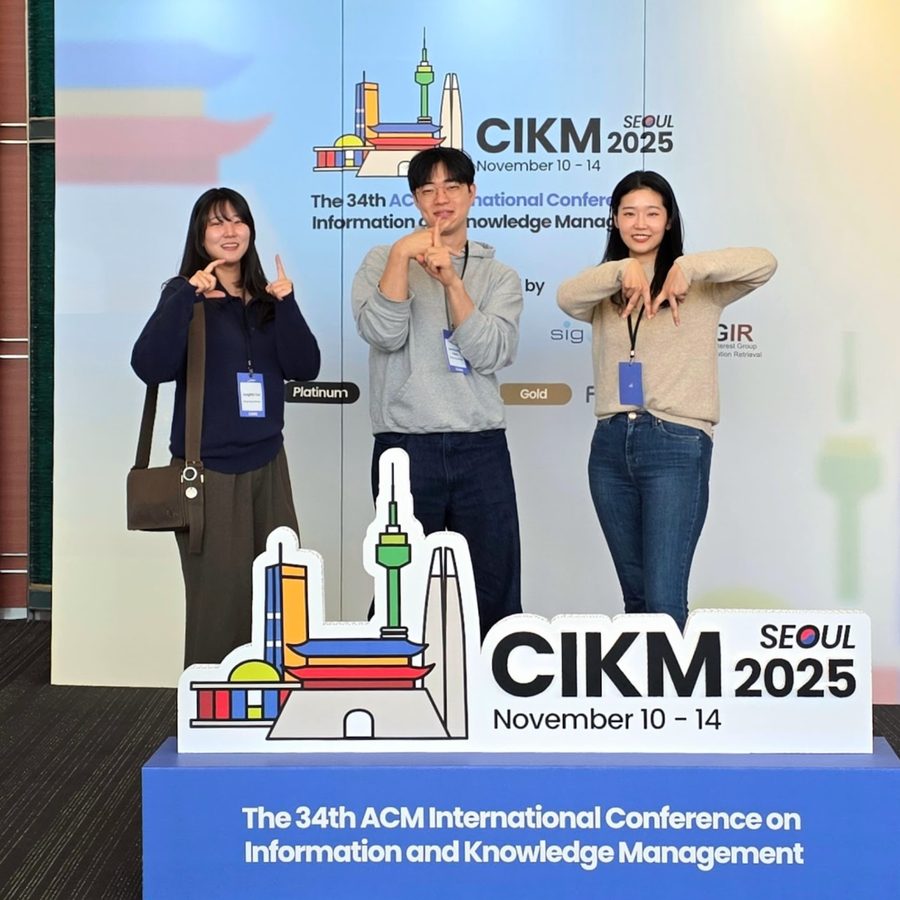 Three lab members posing at the CIKM 2025 sign in Seoul